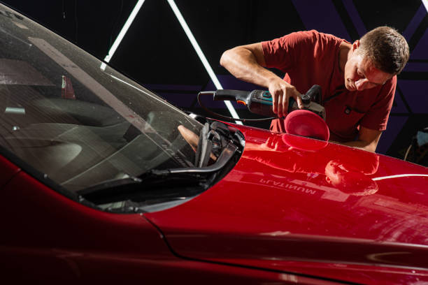 Detailer polishing a red vehicle hood